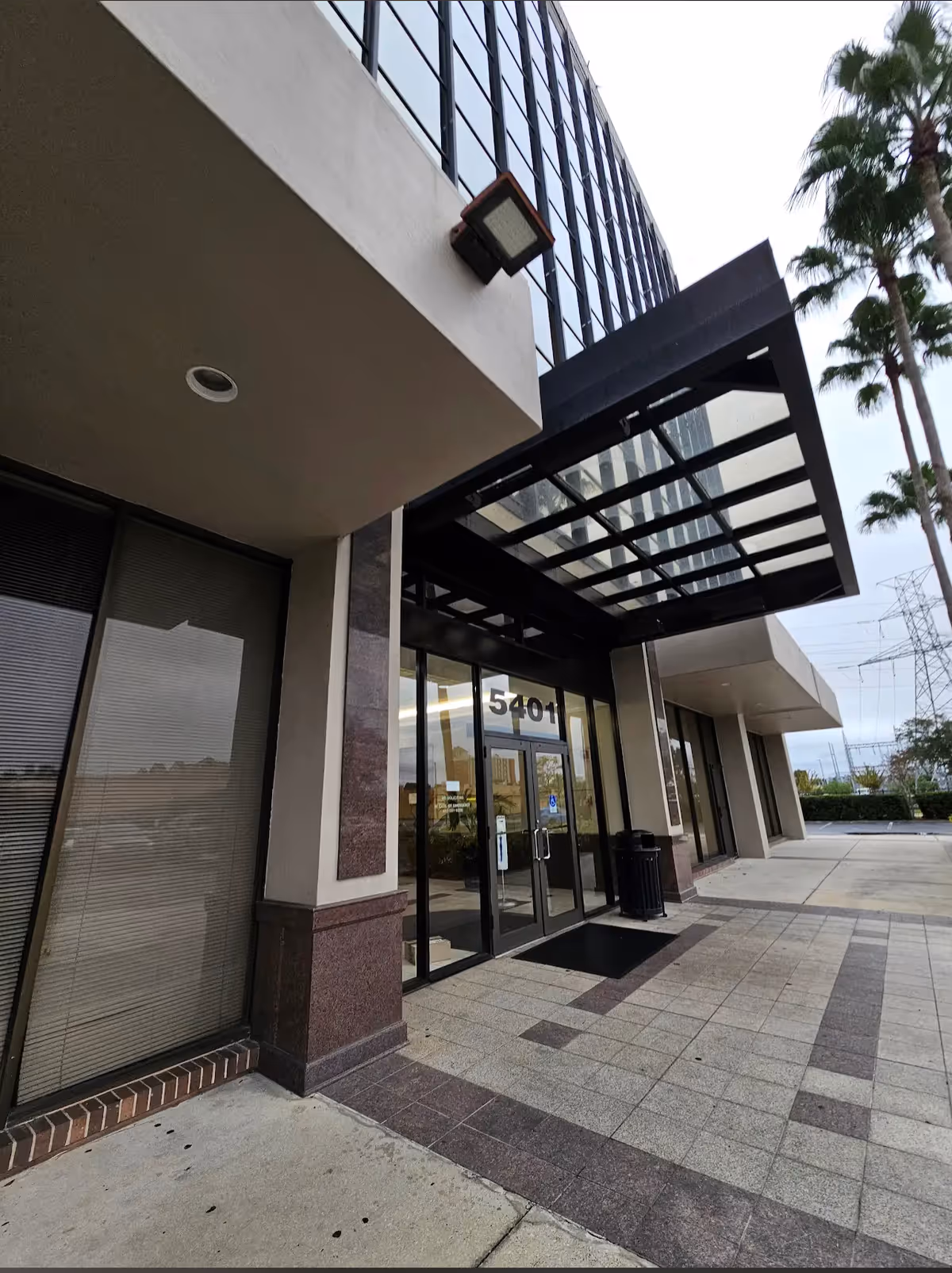 Front exterior of a modern senior living facility with glass doors and a canopy.