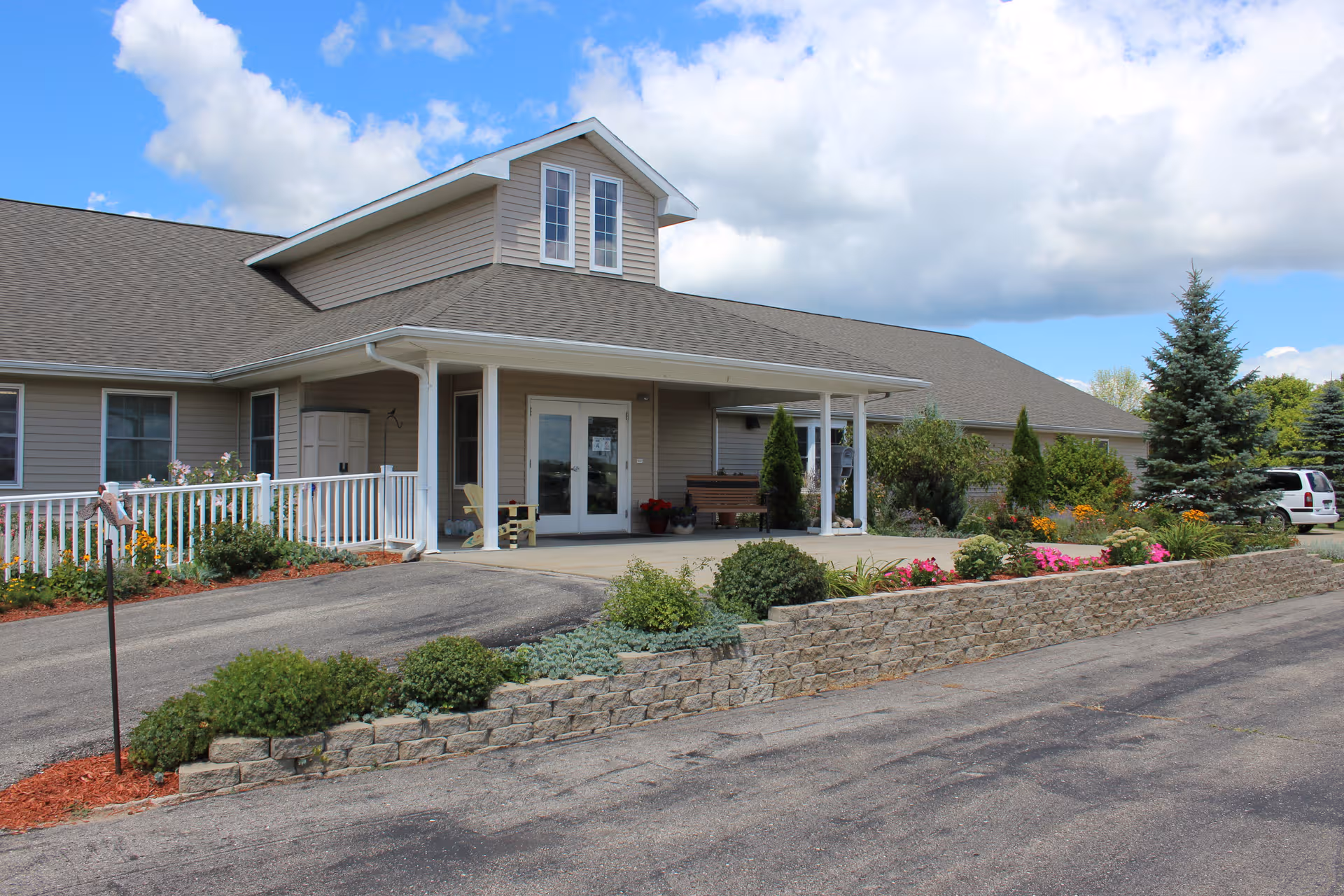 Front exterior of a beige senior living facility with a landscaped stone border.