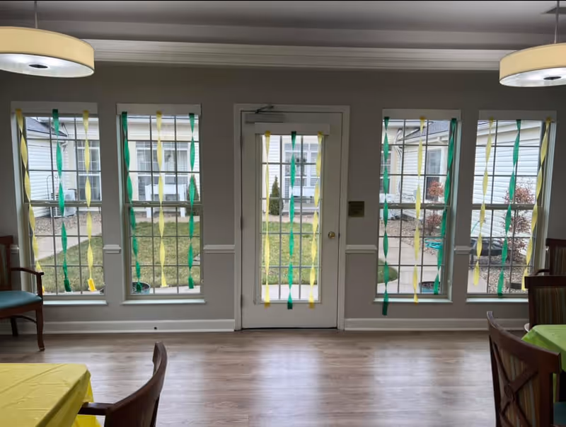 Bright interior room with windows, central door, and green-yellow streamers hanging.