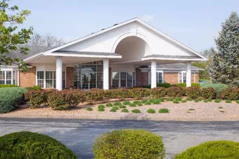 Magnolia Village senior living center exterior featuring white portico arch and manicured landscaping