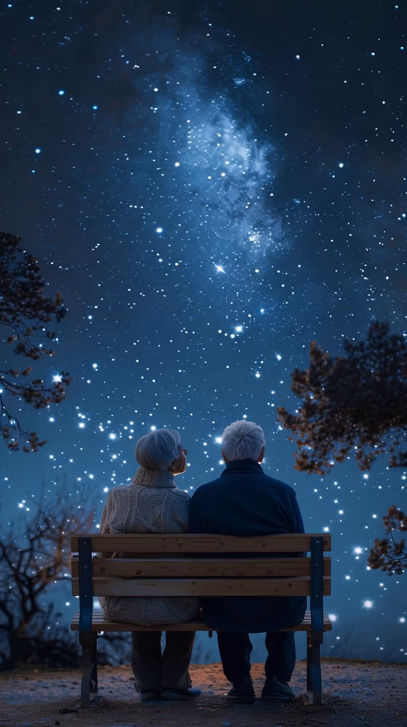 Two elderly people sit on a wooden bench, gazing at a star-filled night sky.
