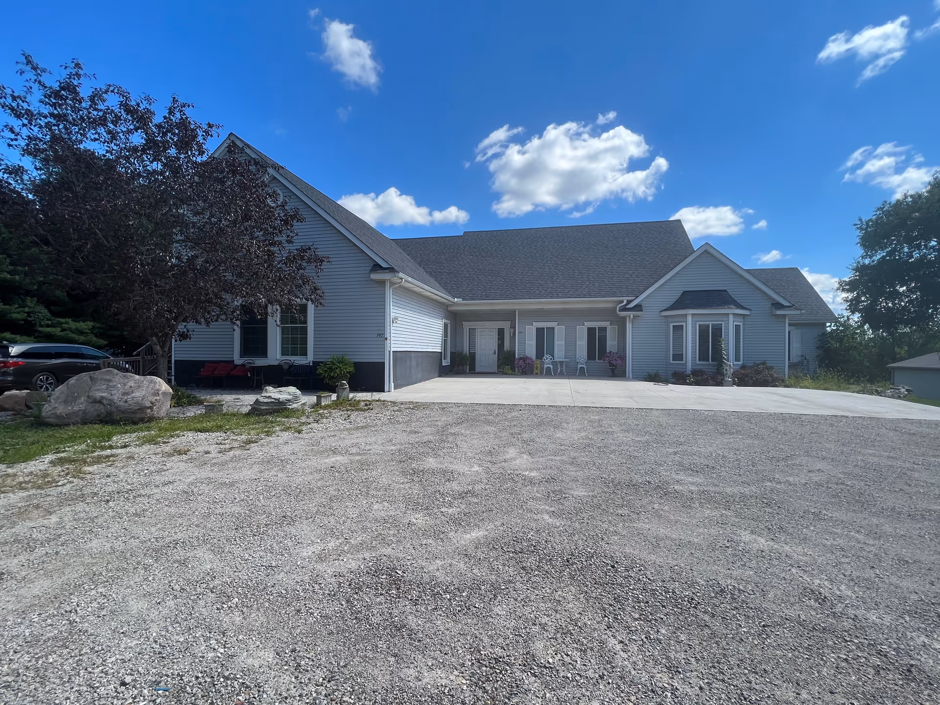 Front view of Addison-Oaks Manor facility with a wide driveway and blue sky