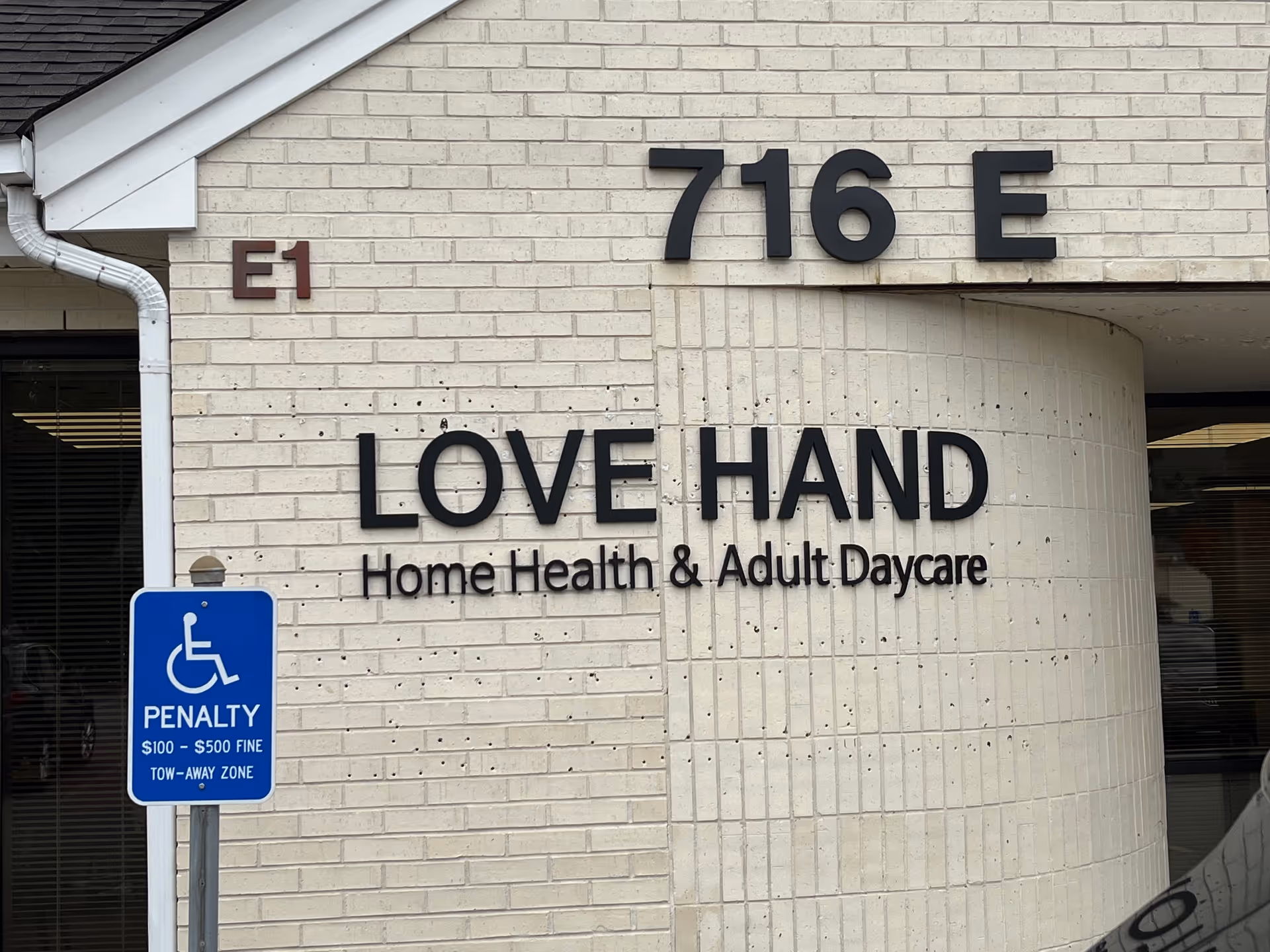 Exterior view of a Love Hand facility with large sign and handicap parking sign.