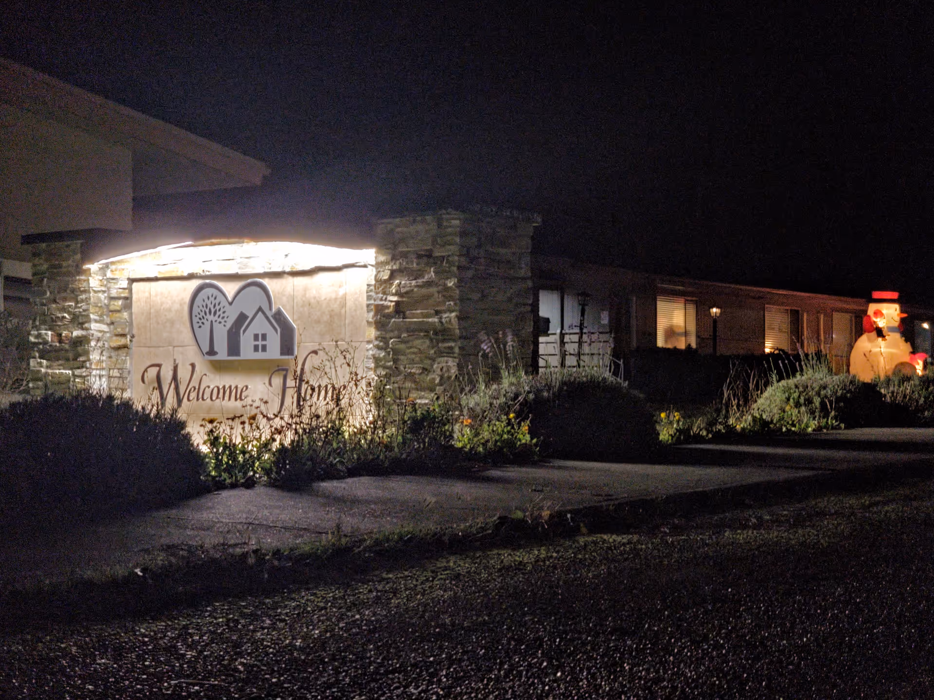 Night exterior of Welcome Home Oak Harbor with lit sign and entrance.
