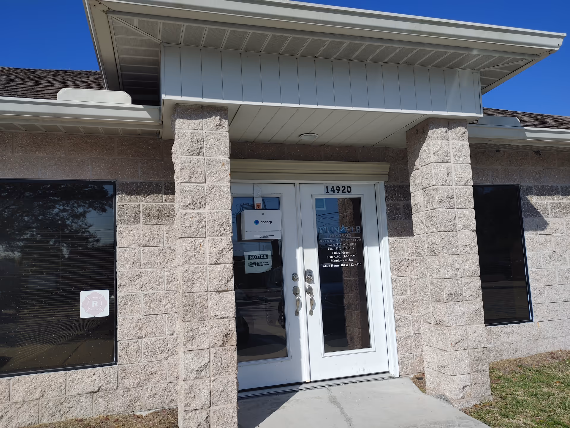 Exterior view of a Pinnacle Home Care facility entrance with glass doors and stone pillars.