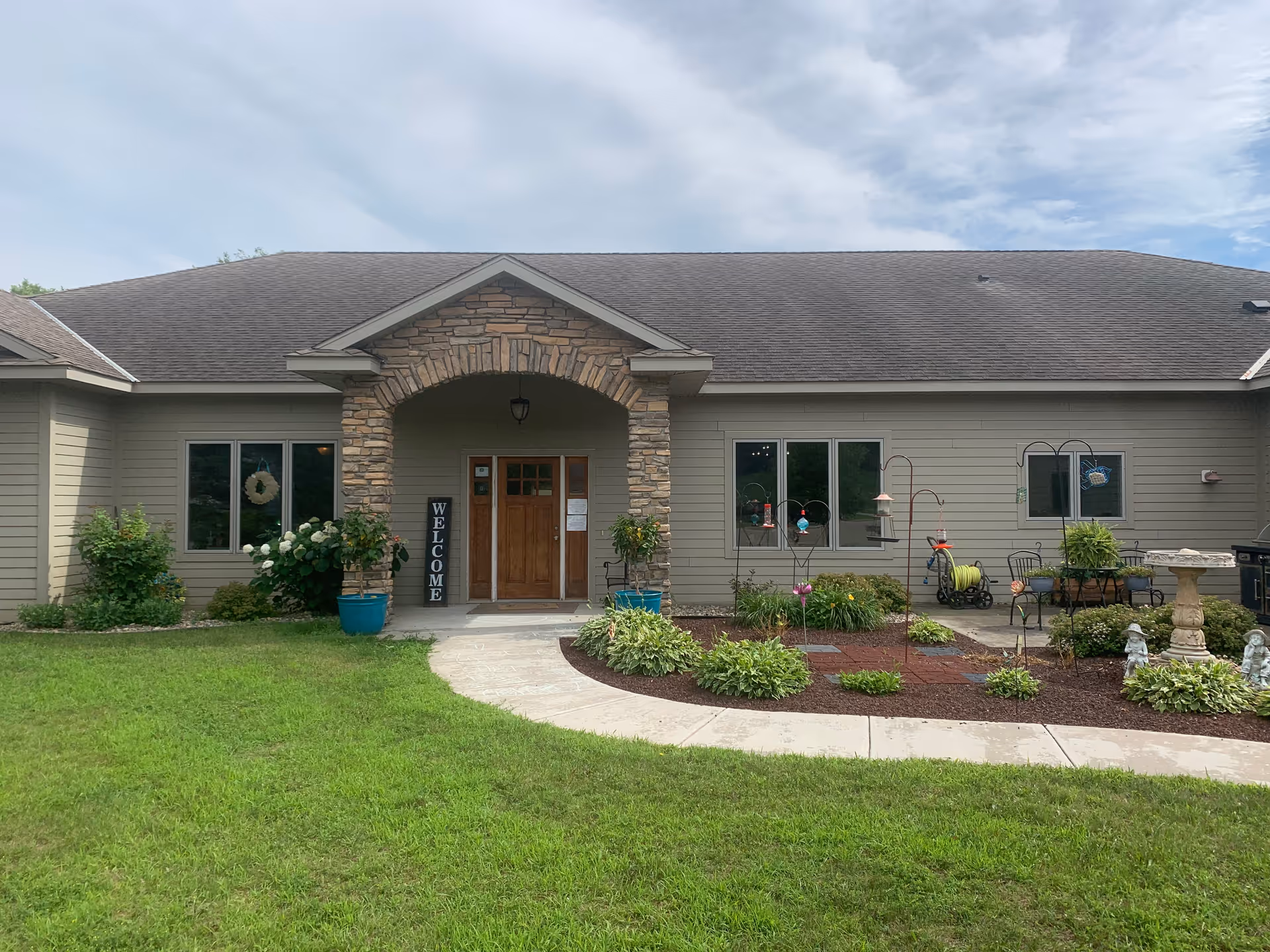 Front exterior of Cannon Country Senior Living with stone arch entrance and garden.