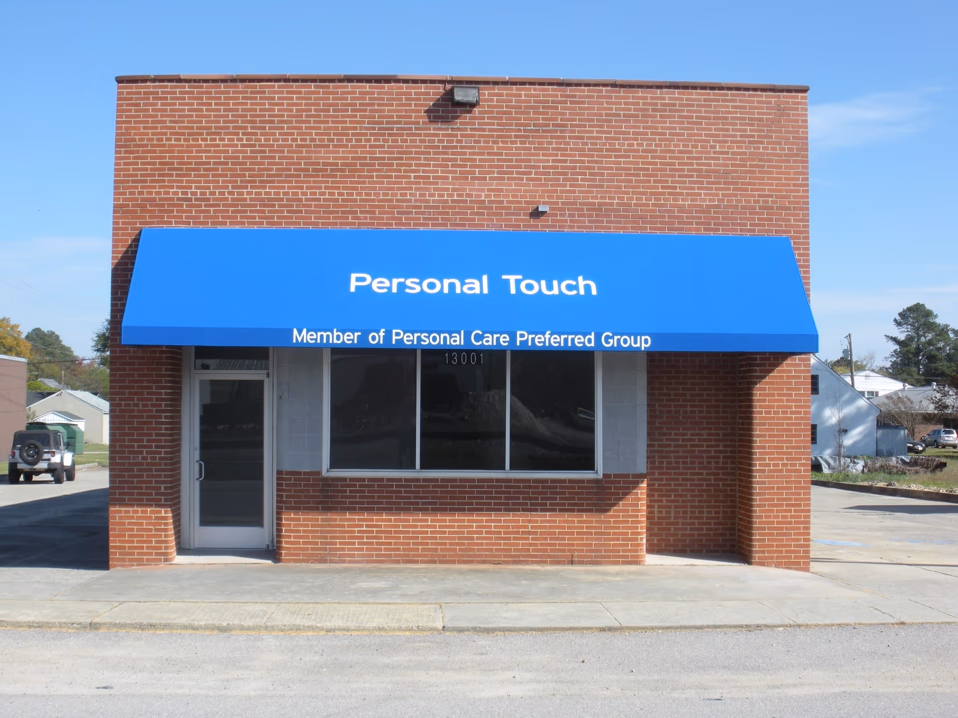 Brick building exterior with a blue awning labeled Personal Touch over the front window.