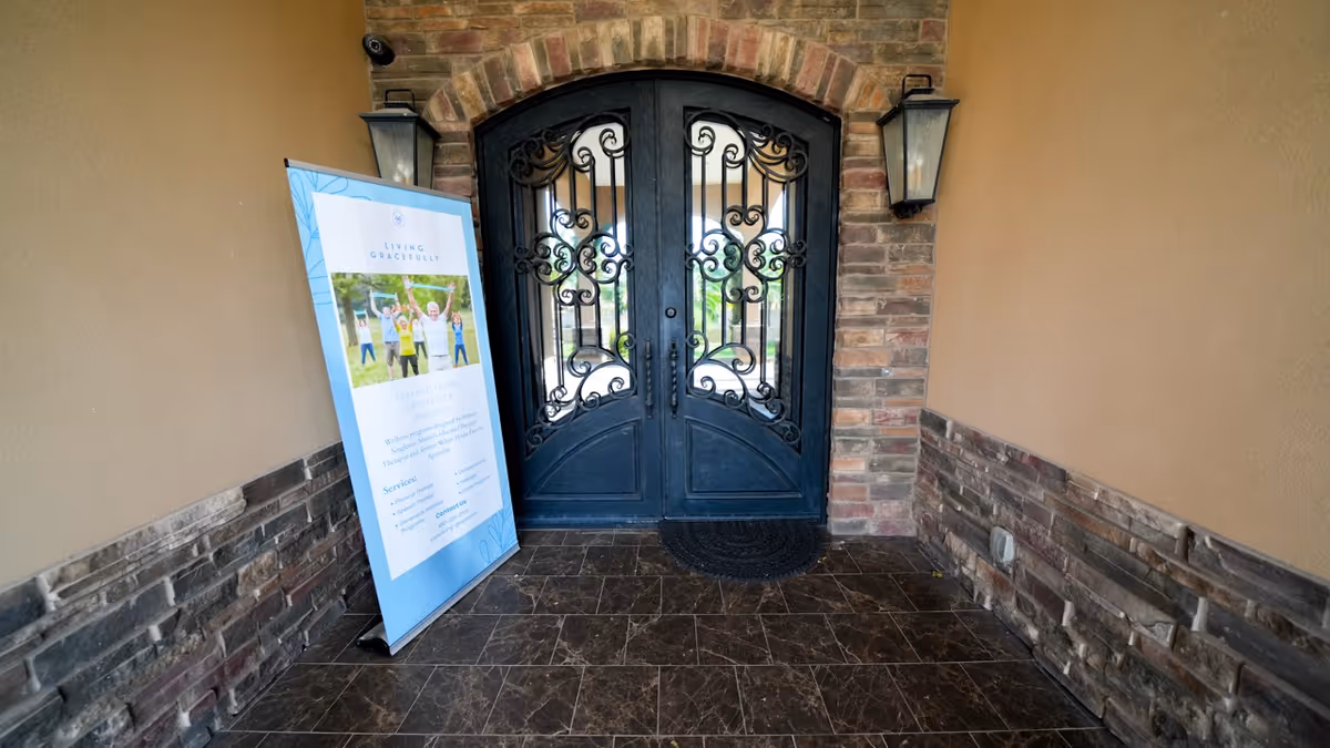 Decorative wrought-iron double doors at an entry, with a blue informational sign on a tiled entryway.
