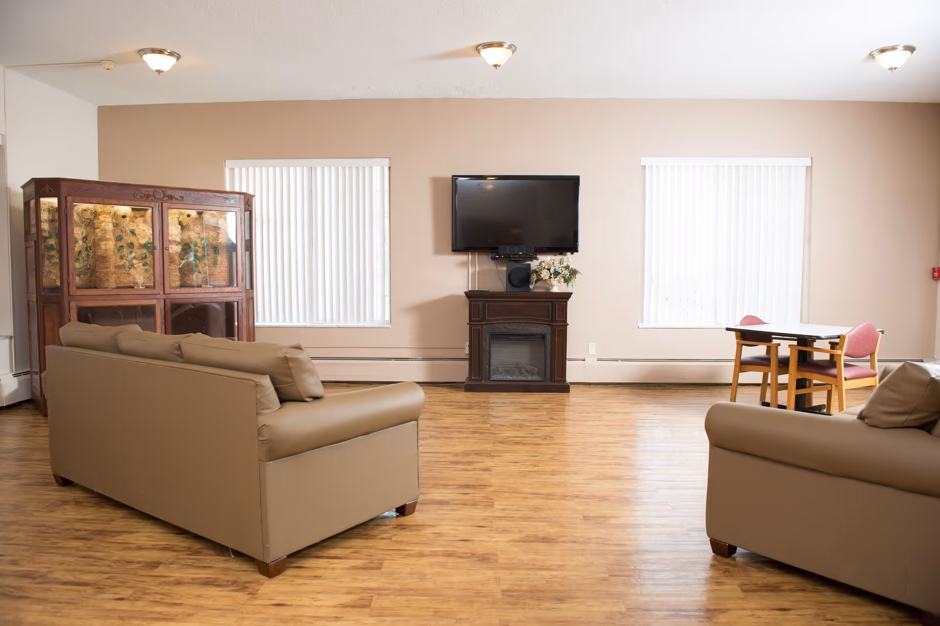 Neutral living room with two beige couches, a fireplace, TV, and a small table.