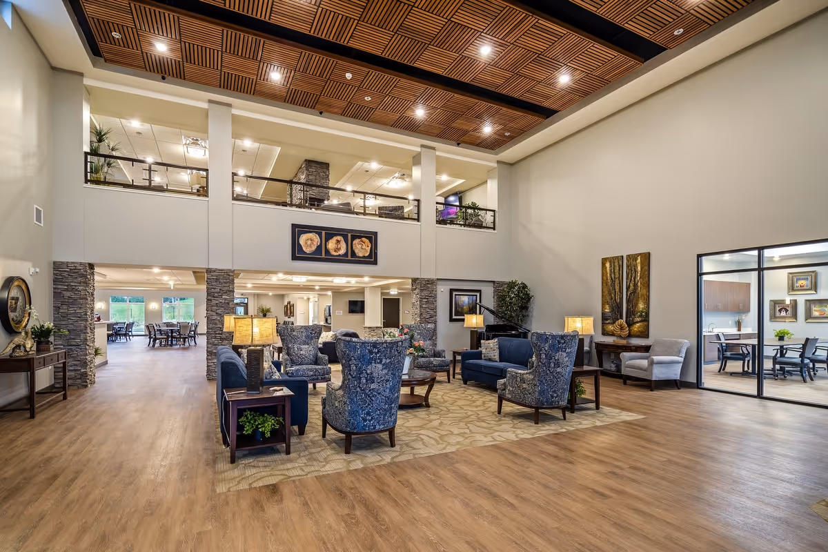 Spacious senior living lobby with blue upholstered chairs and a second-floor overlook.