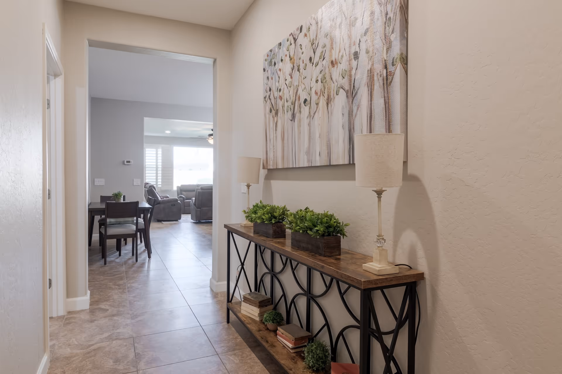 Hallway with console table, artwork, lamps, and a view into a seating area.