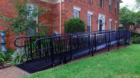 Exterior brick building with a long black accessibility ramp along a grassy yard.