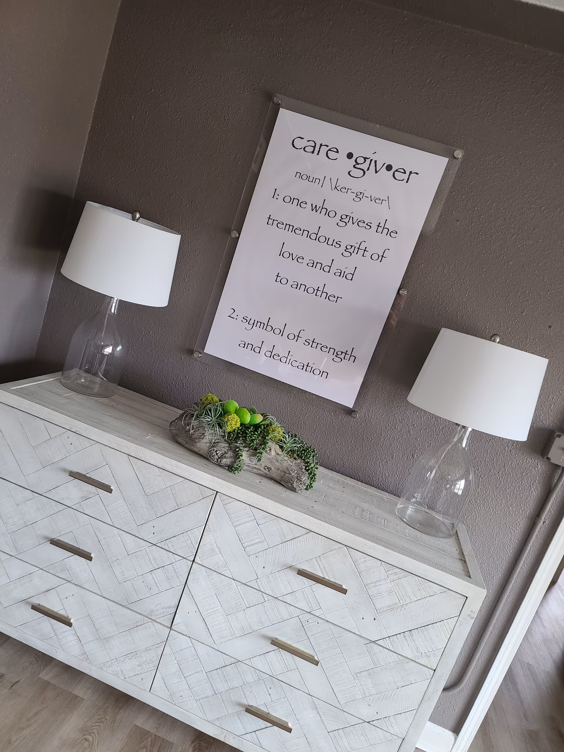 A decorative dresser with two lamps and a wall plaque in a living space.