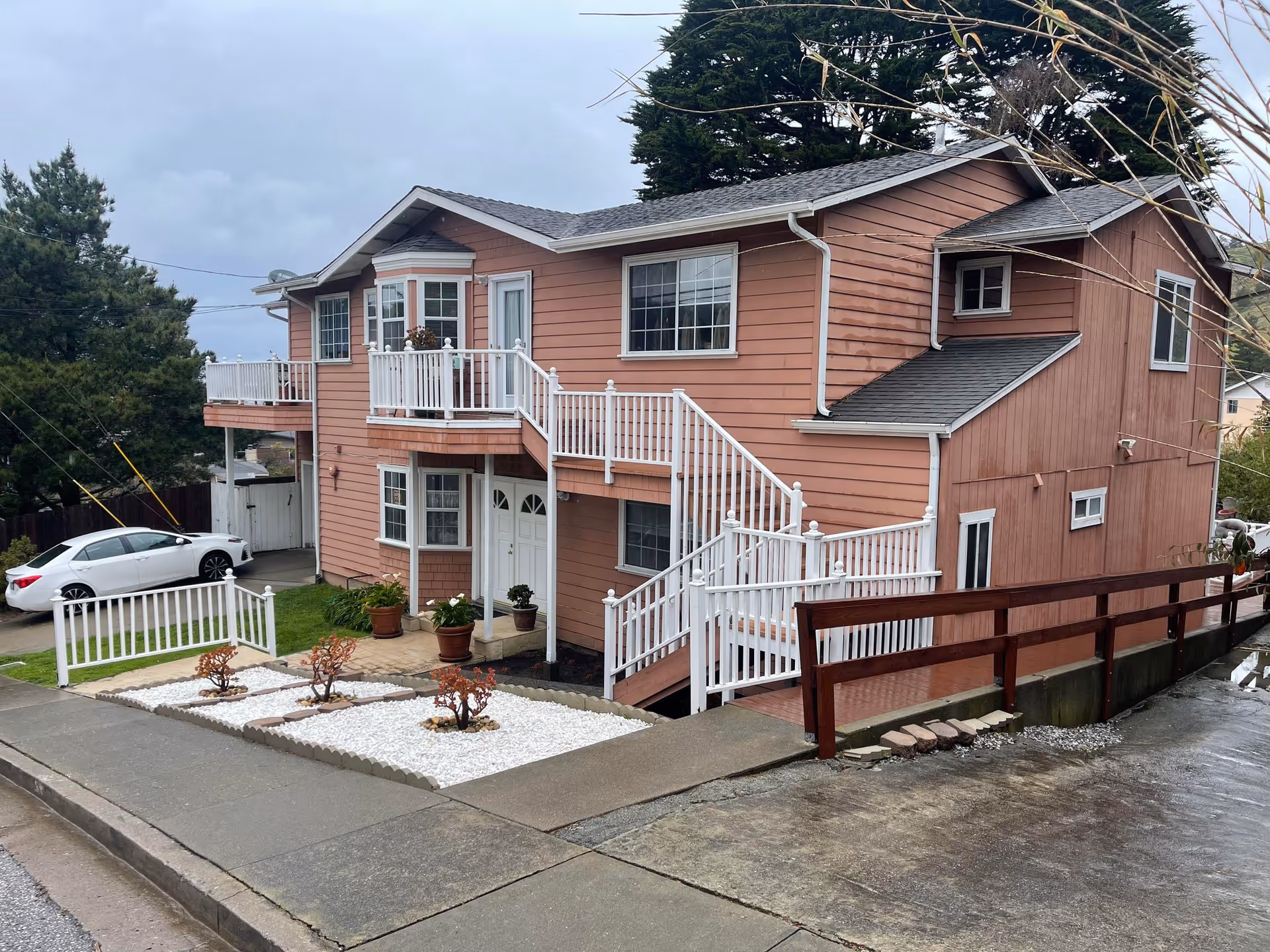 Two-story peach-colored senior living building with white railings and exterior staircases.
