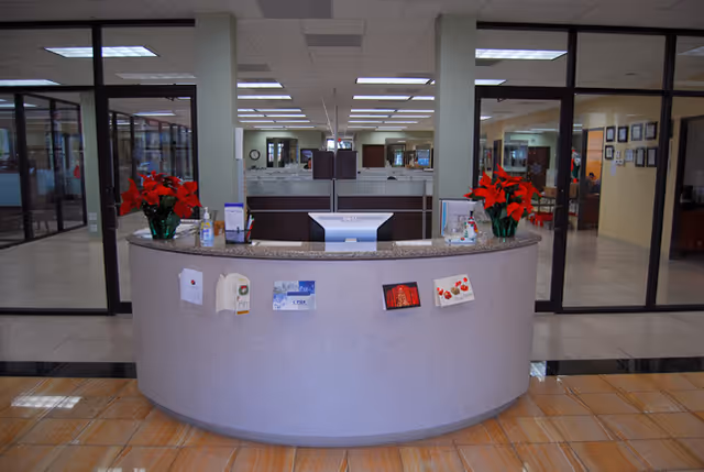 Curved reception desk in a bright lobby with red poinsettias and brochures.