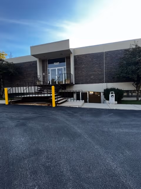 Front view of a brick building entrance with stairs and a ramp