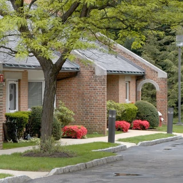 Exterior view of a brick senior living facility front with landscaping and an archway.