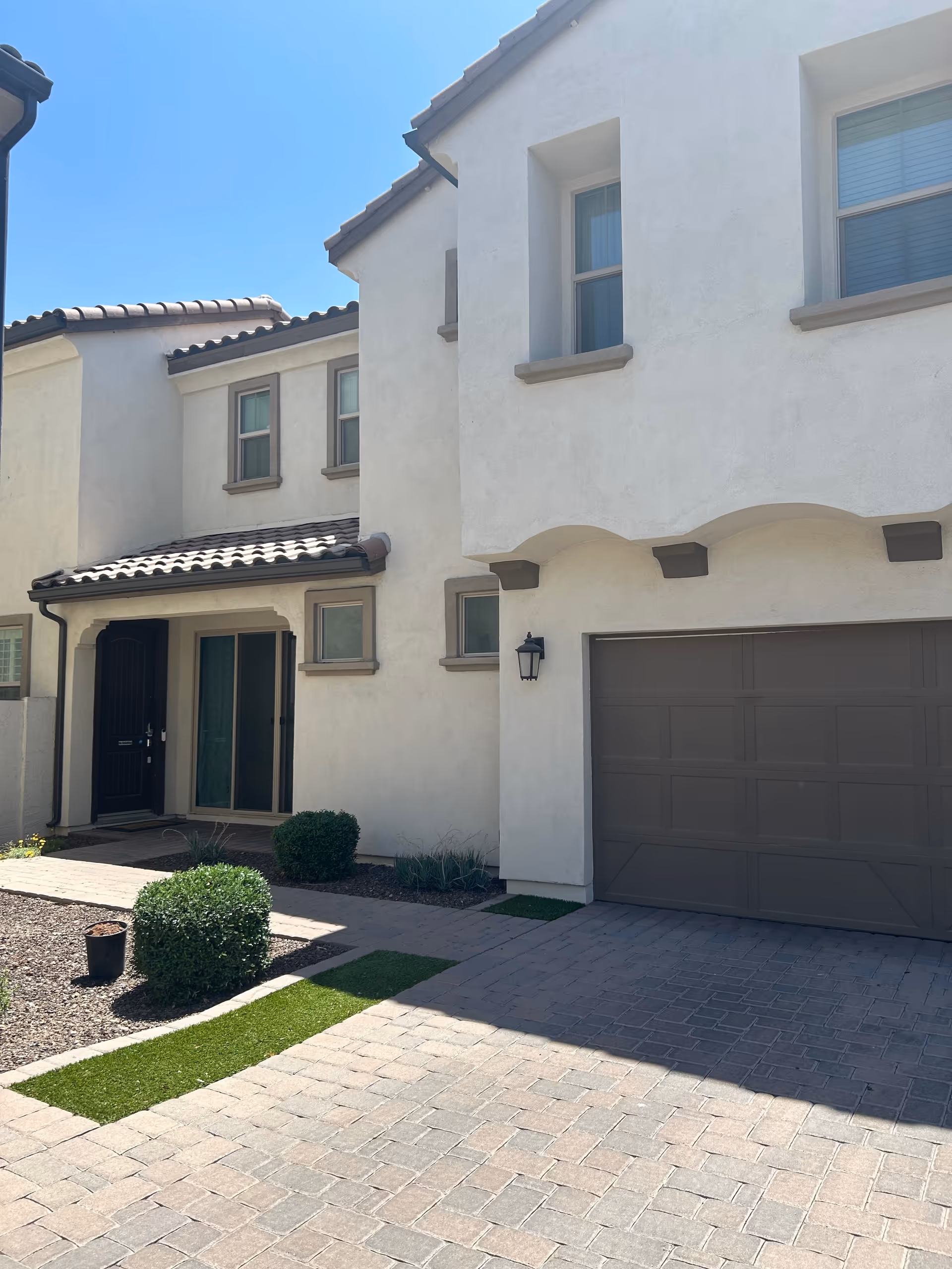 White stucco senior living building exterior with driveway, garage, and landscaped entrance.