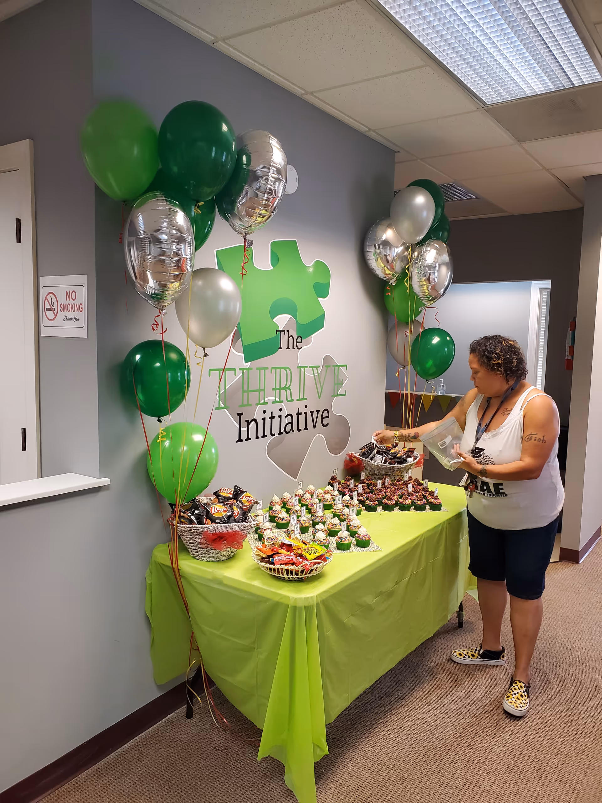 Indoor reception area with a lime green table, balloons, and a staff member arranging snacks.