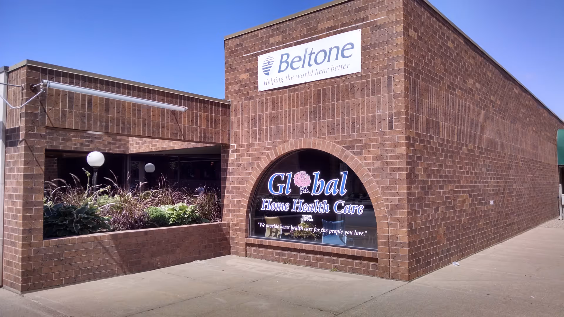 Brick building exterior with a Beltone sign and a Global Home Health Care window display.