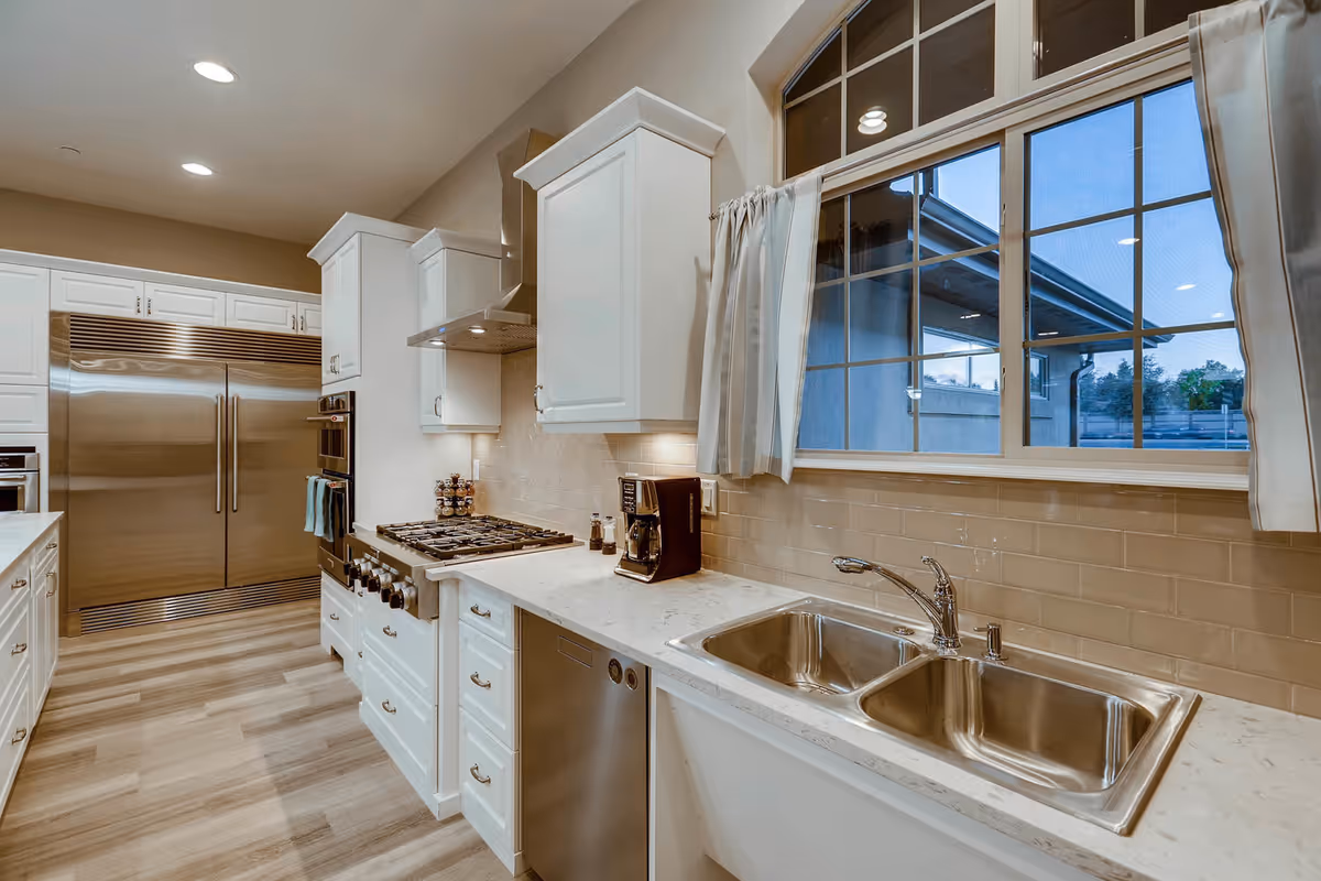 Bright, modern kitchen with white cabinets, stainless steel appliances, and a large window.