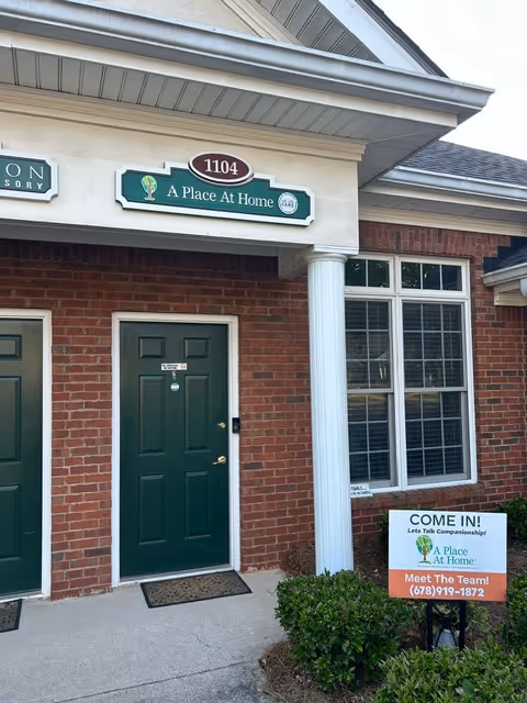 Front exterior of A Place At Home Alpharetta, with green door and sign.