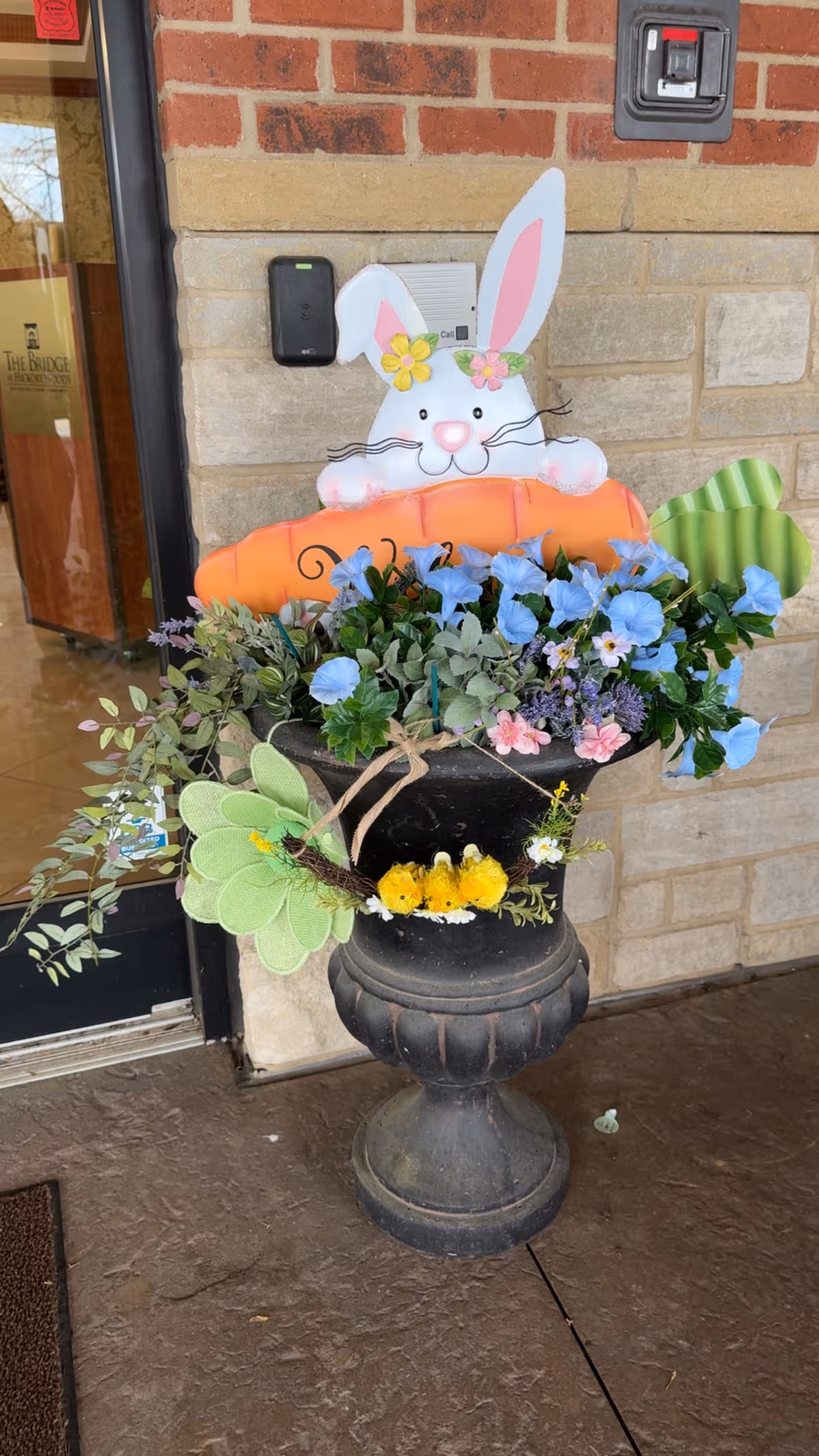 Decorative bunny and colorful flowers in a planter outside the building entrance.