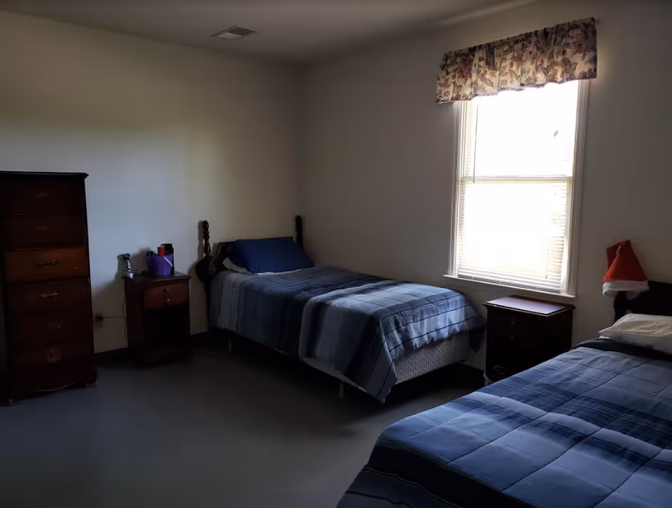 Two twin beds with blue quilts and dark wood furniture in a shared bedroom.