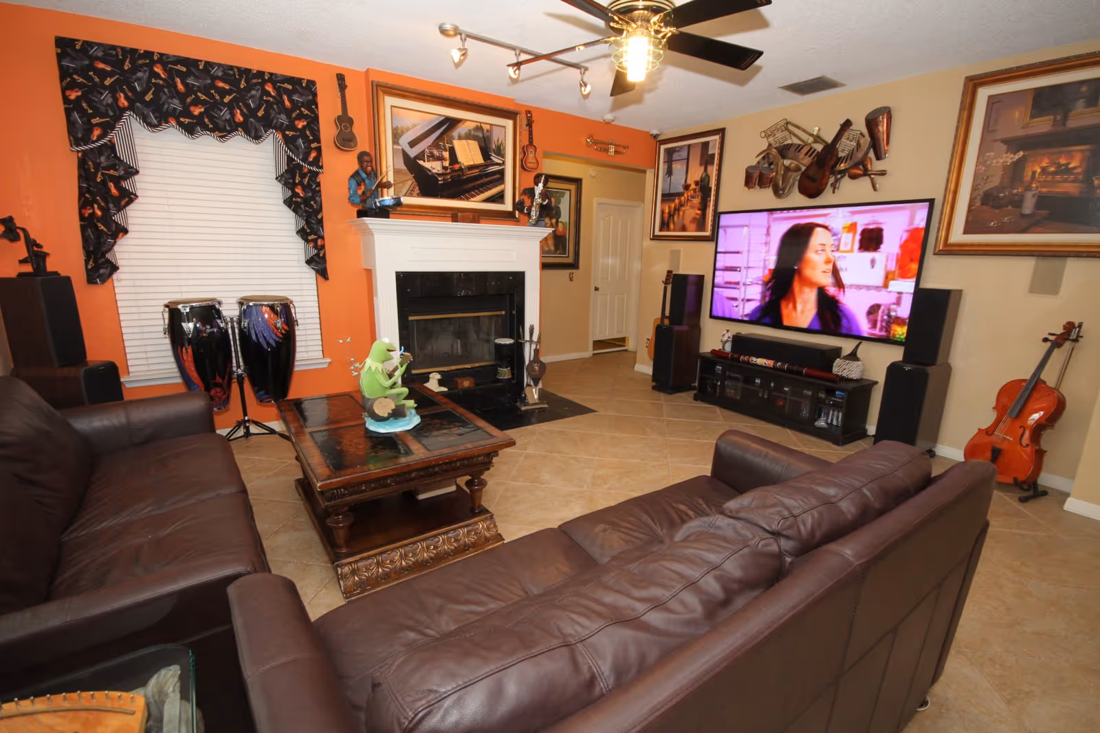 Cozy living room with leather sofas, fireplace, guitar decor, and a large television.