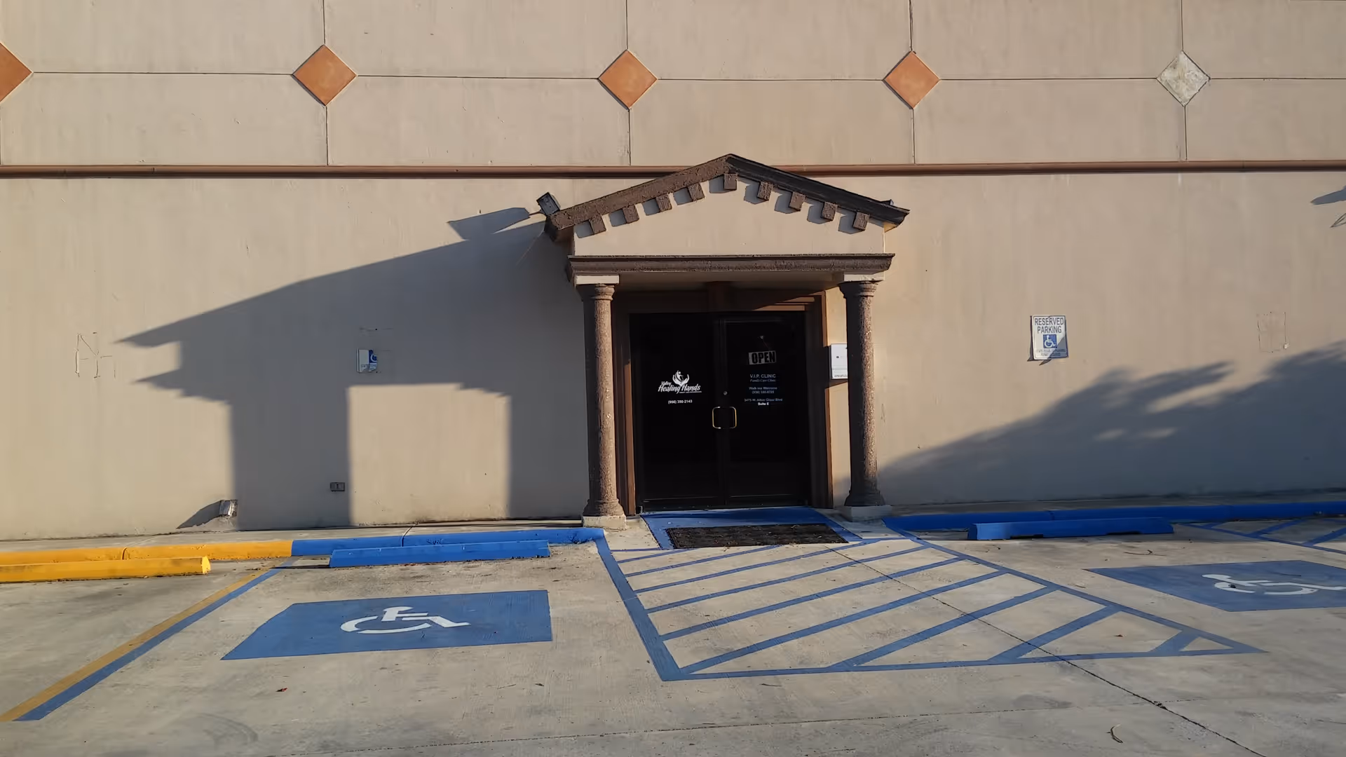 Beige facility building with a small columned entrance and accessible parking in front.