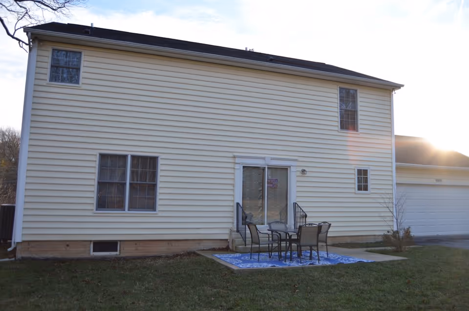 Exterior view of a beige two-story facility with a small patio and outdoor furniture.