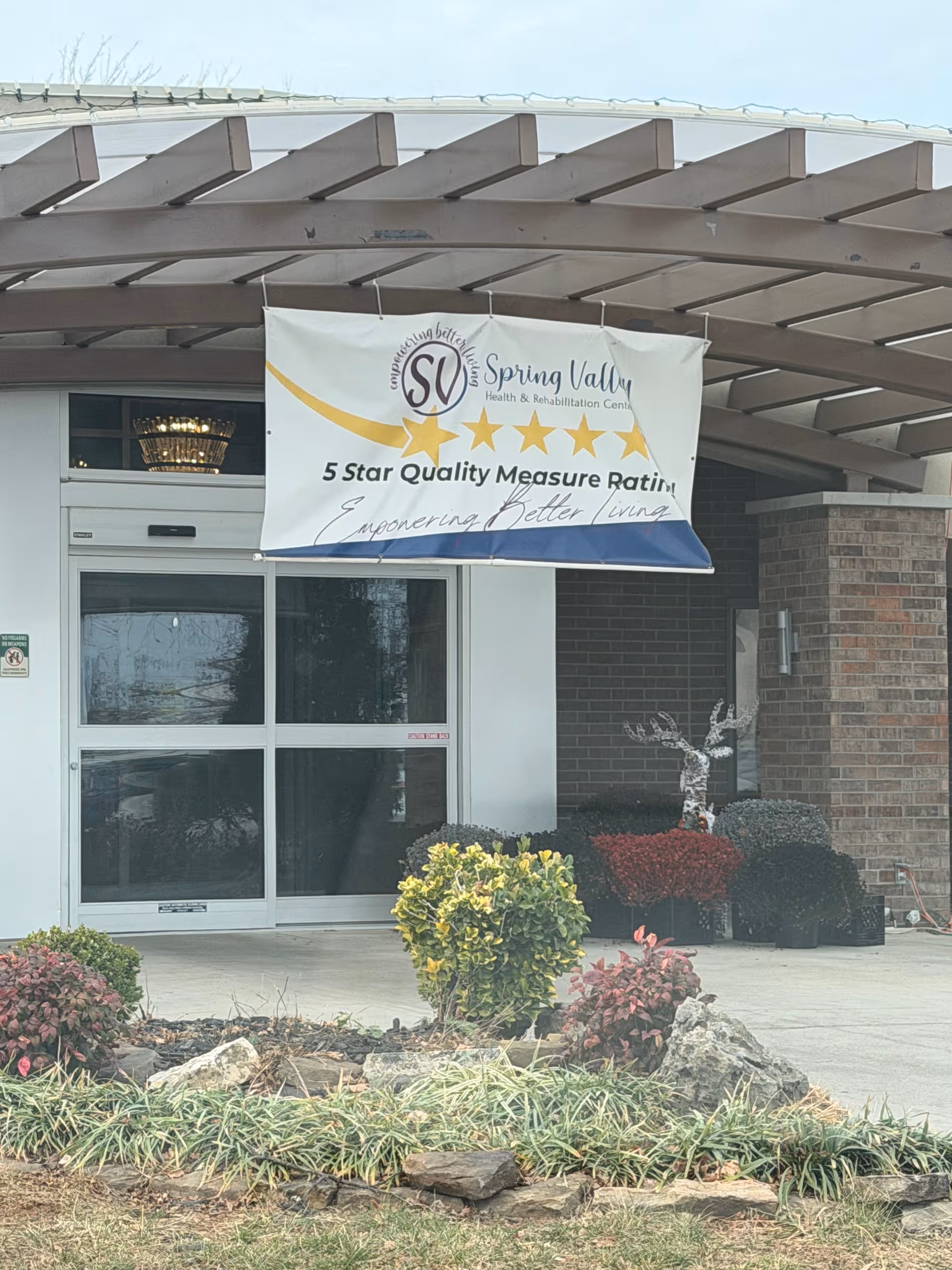 Entrance of Spring Valley Health and Rehabilitation Center with a banner above glass doors.