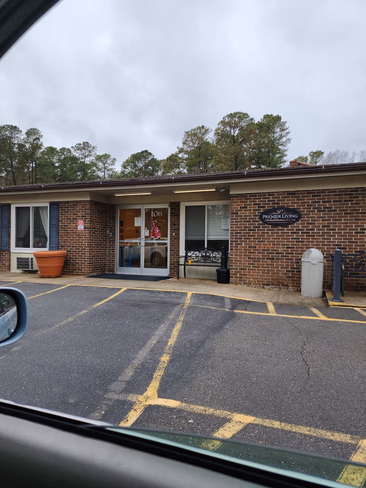 Brick Premier Living entrance with glass doors, sign, and a parking lot.