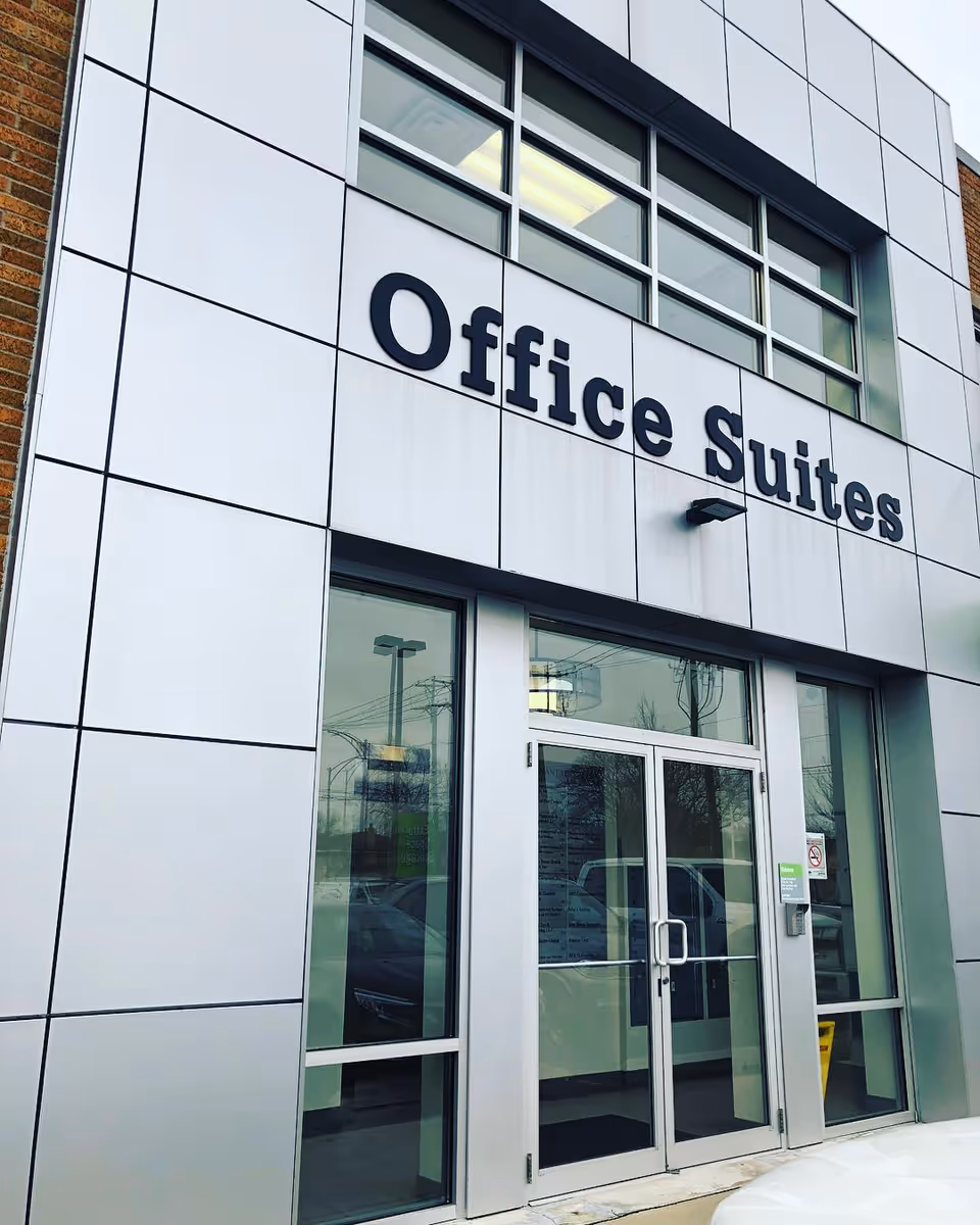 Modern exterior of a building with 'Office Suites' sign and glass entrance doors.