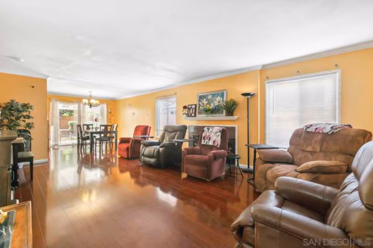 Bright living room with yellow walls, brown leather recliners, and a dining area in back.