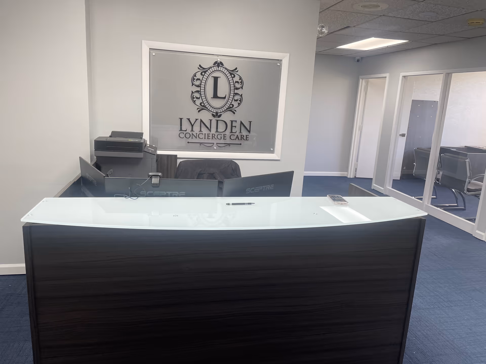 Reception desk in a Lynden Concierge Care lobby with a branded wall sign.