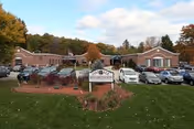 Exterior view of Oakdale Rehabilitation and Skilled Nursing Center with a parking lot and trees.