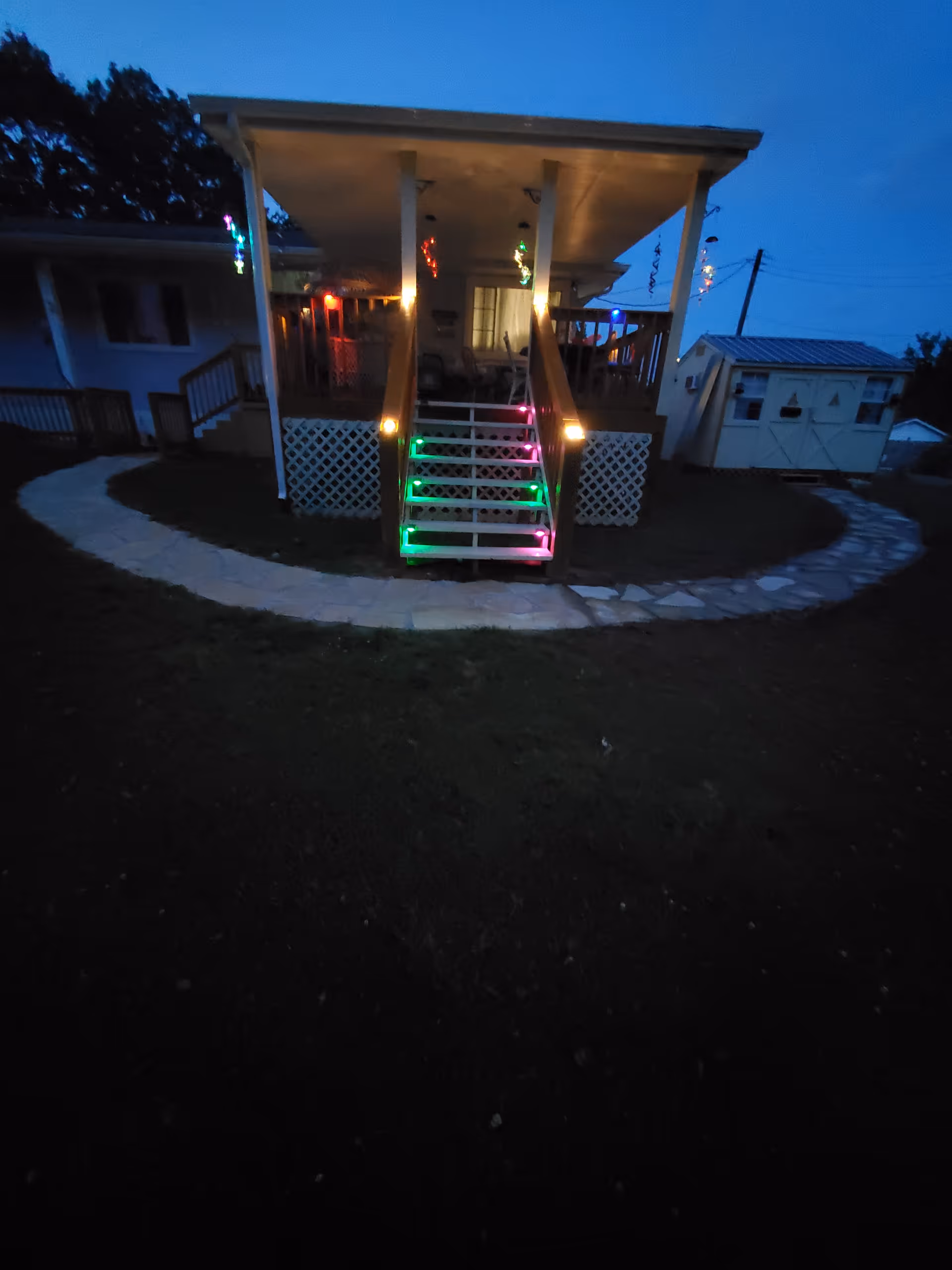 Nighttime exterior of a small porch with colorful lights on the steps