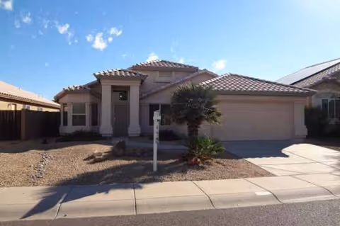 Front exterior view of a single-story home with a two-car garage and desert landscaping.