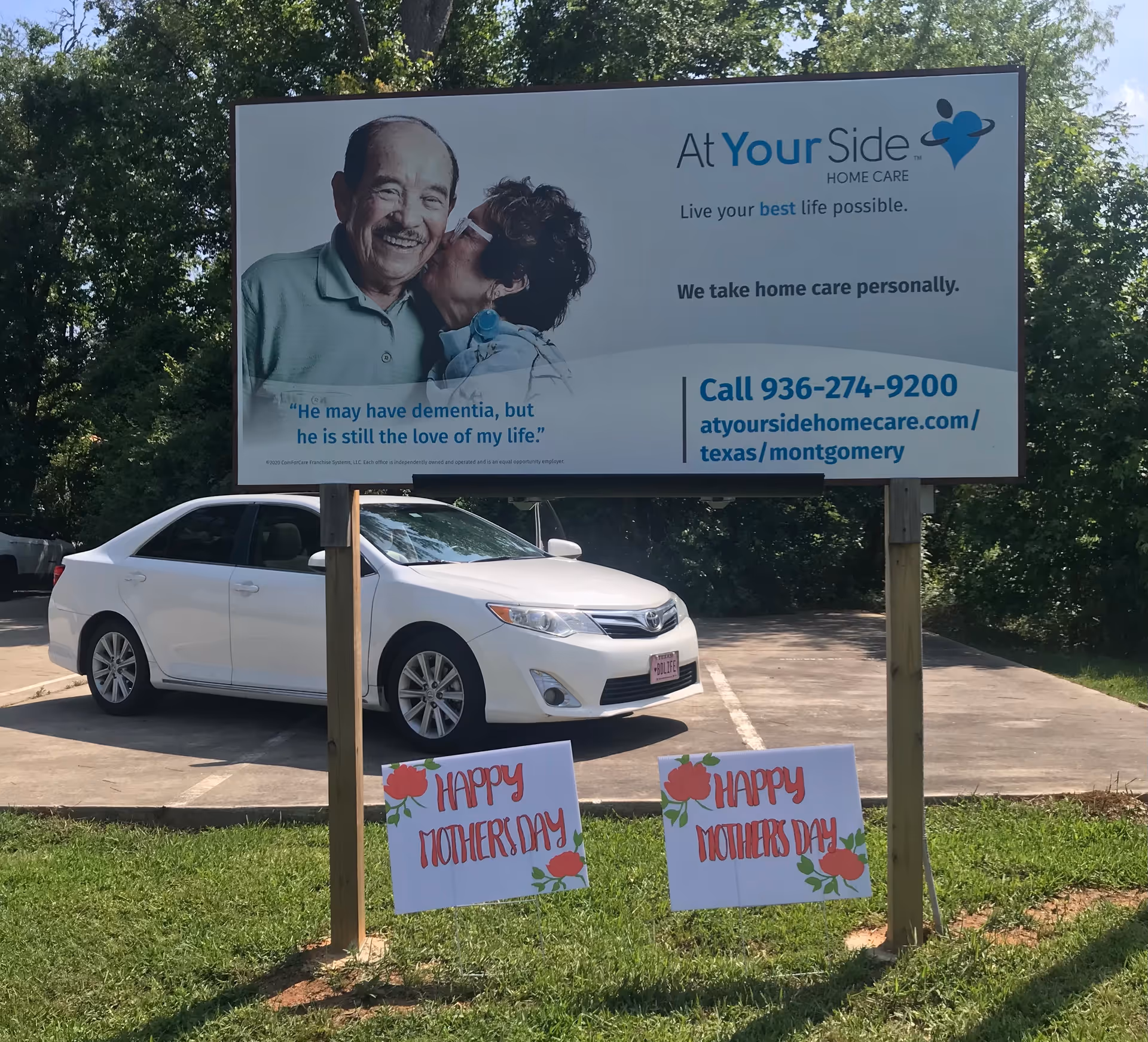 Large outdoor billboard for At Your Side Home Care with a white car parked beneath.