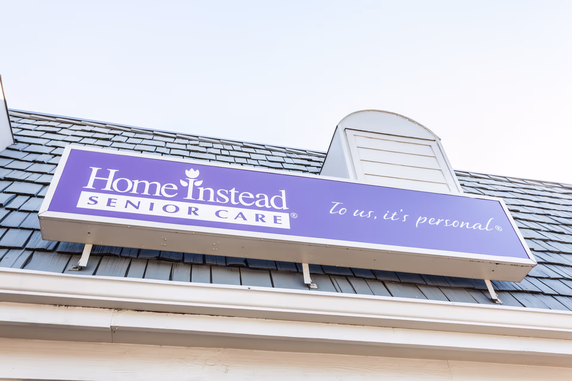Purple Home Instead Senior Care sign mounted on a building exterior