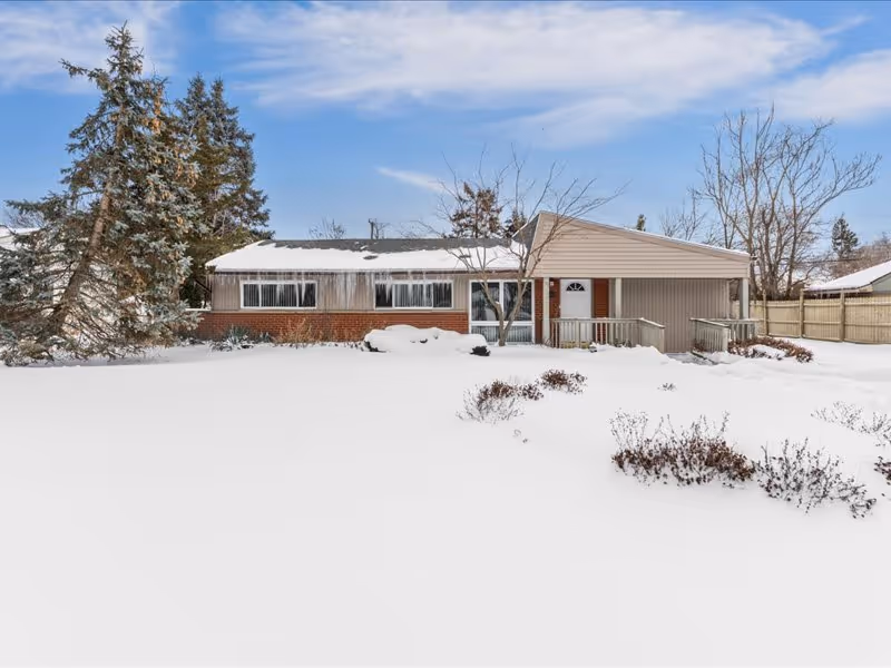Single-story ranch-style building with brick and siding facade, a front porch, and a snow-covered yard with trees.