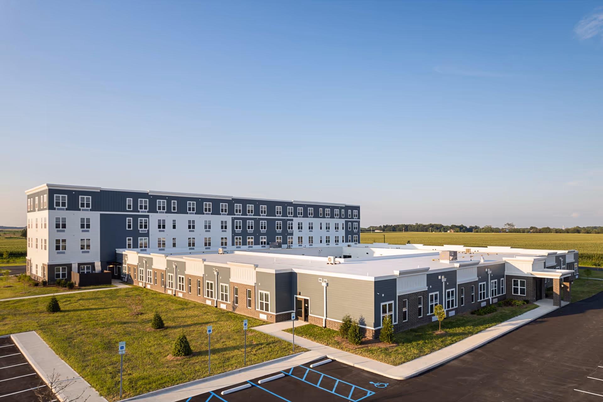 A large modern senior living campus with blue-gray building exterior and surrounding parking.