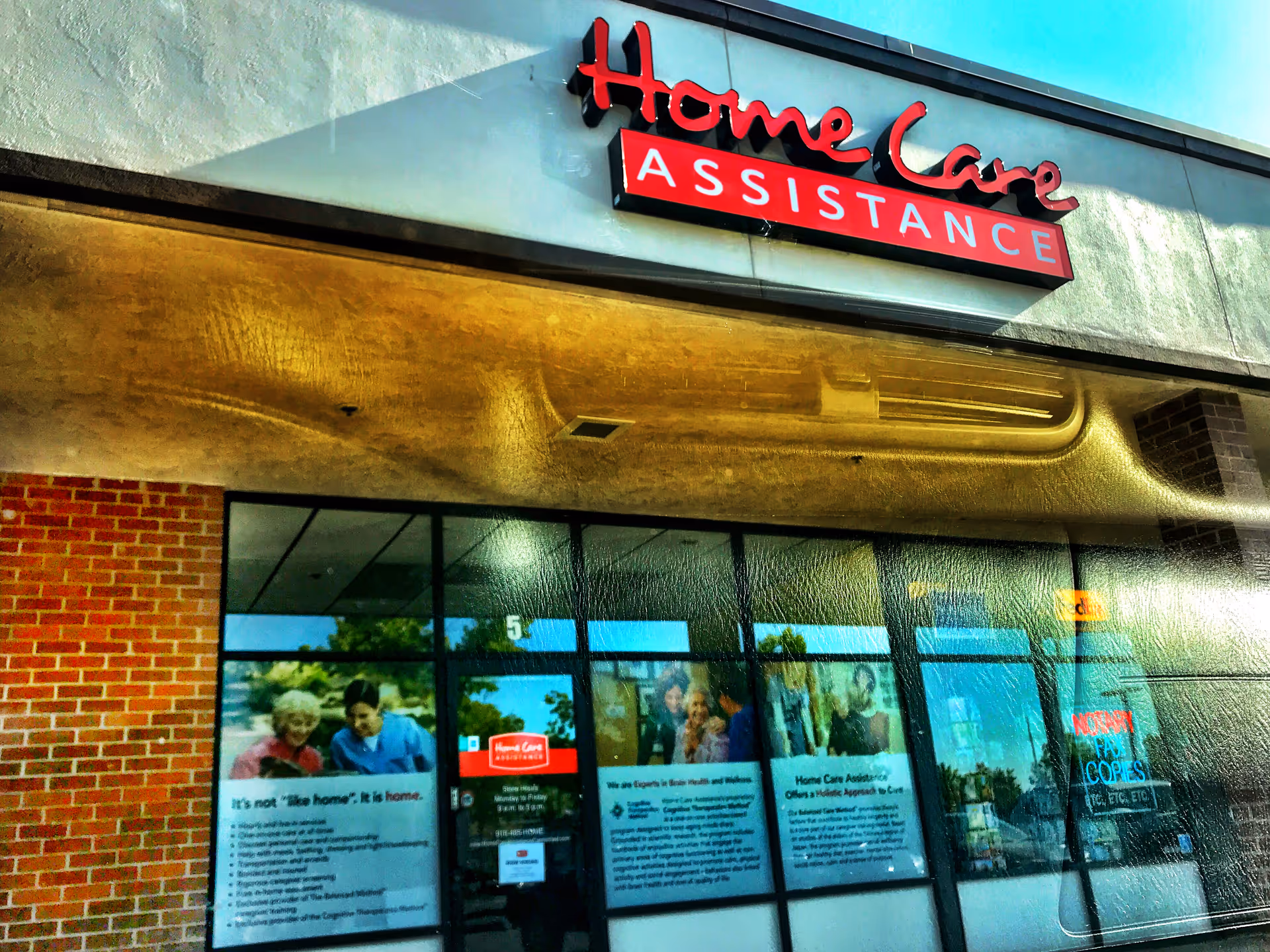 Storefront of Home Care Assistance with red-and-white sign on brick exterior.