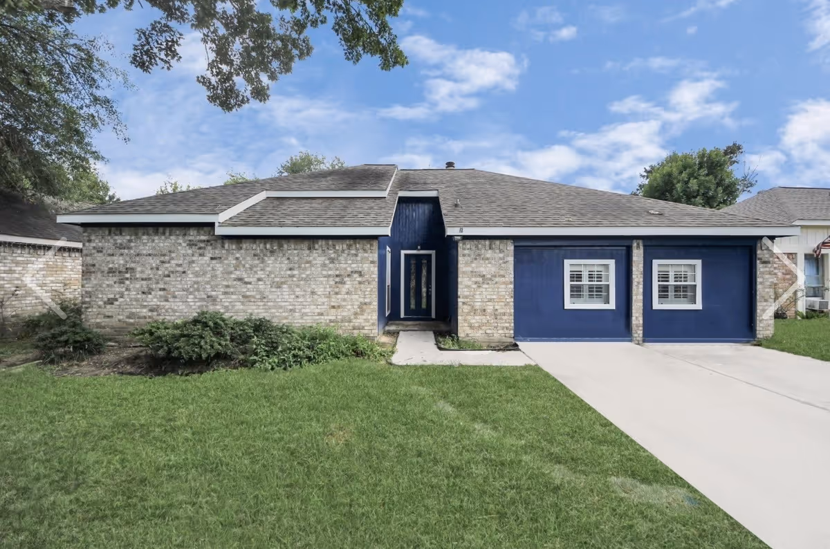 Front exterior of a single-story senior living facility with blue walls, stone accents, and a driveway.
