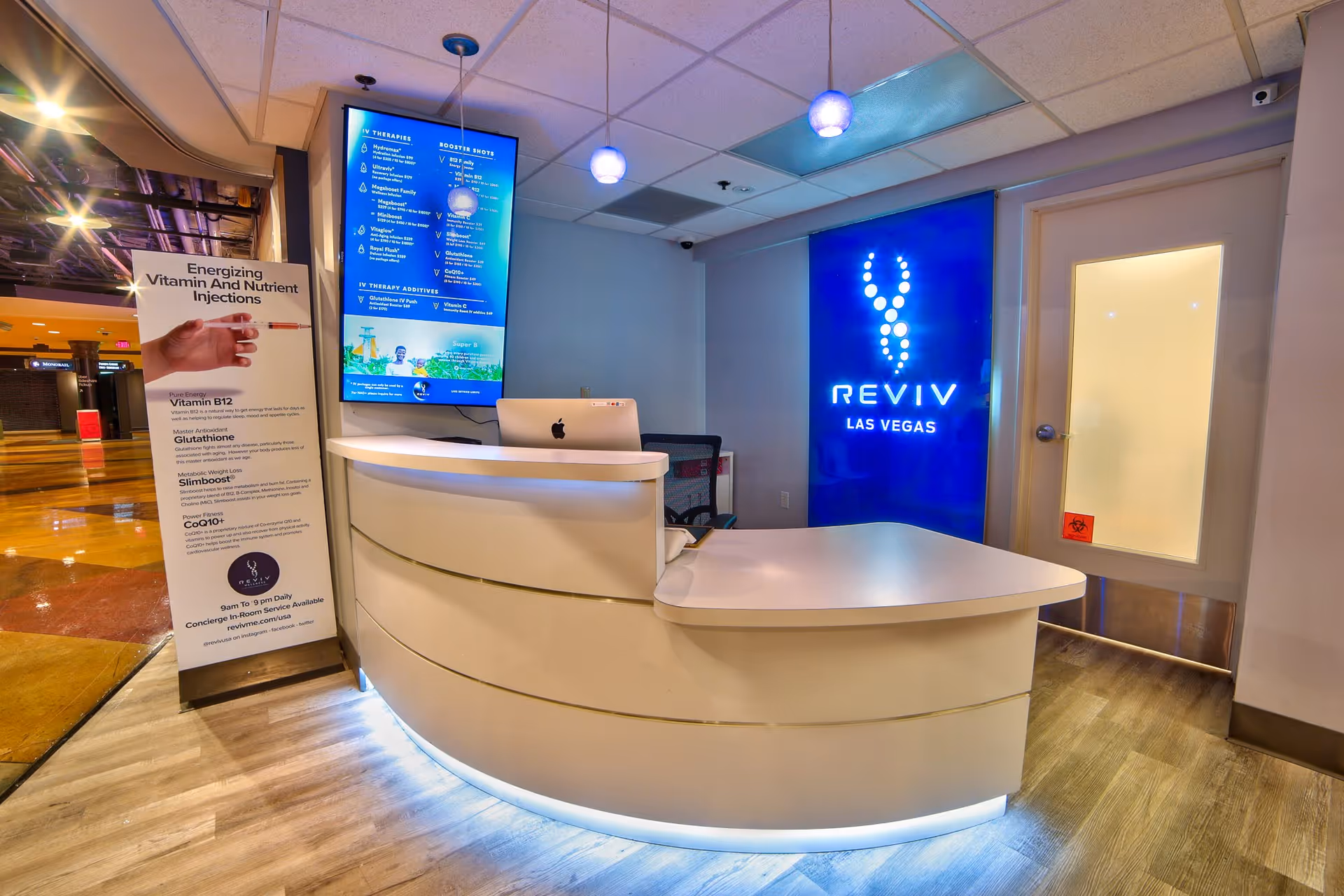 Reception desk in a modern IV therapy lobby with a bright blue Reviv Las Vegas sign.