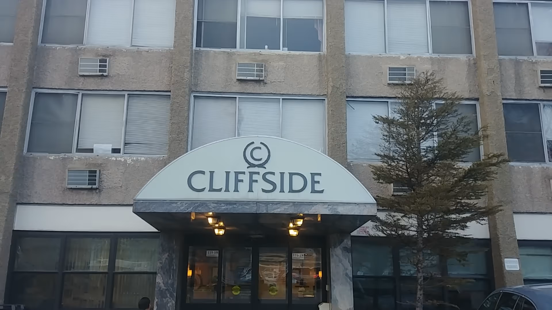 Exterior view of Cliffside facility entrance with arched sign and tree.