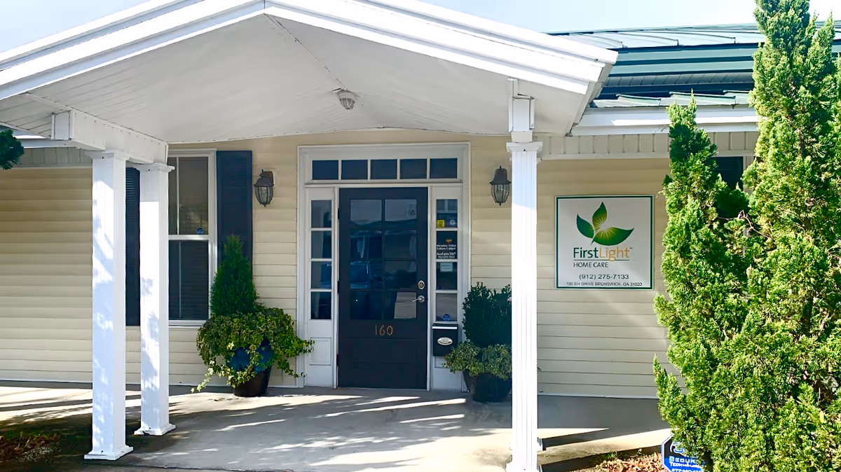 Exterior entrance of FirstLight Home Care Brunswick with columns, doors, and potted plants.