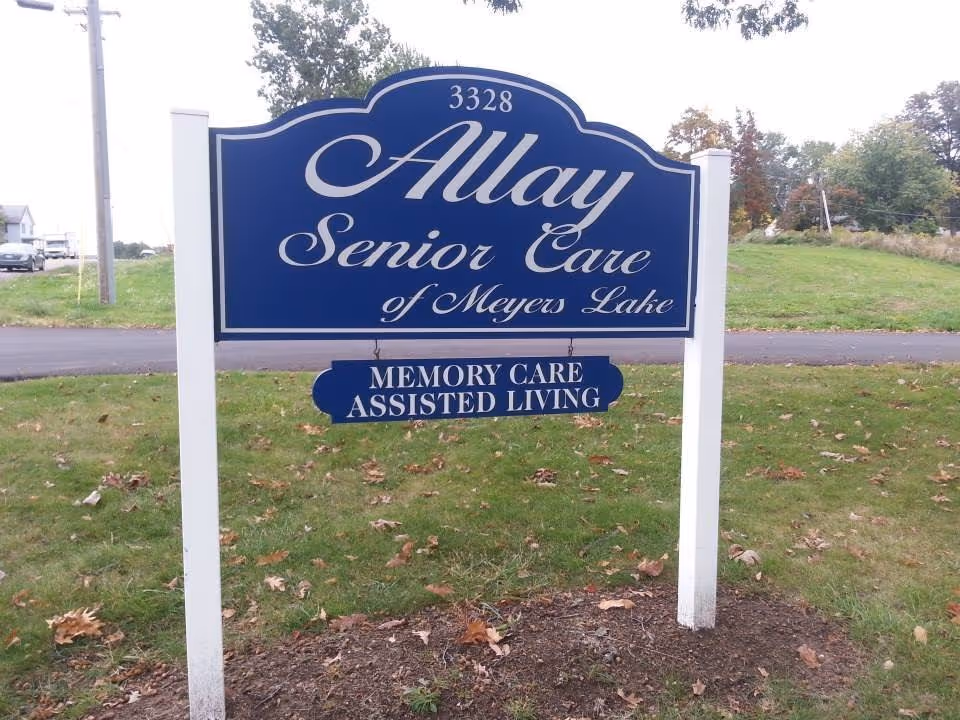 Blue Allay Senior Care sign on white posts in grassy area.