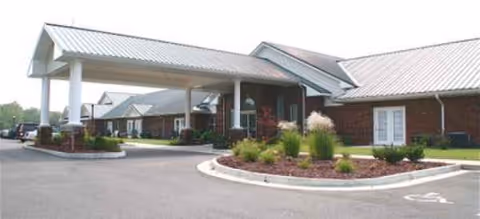 A senior living facility with a covered entrance, driveway, and manicured landscaping.
